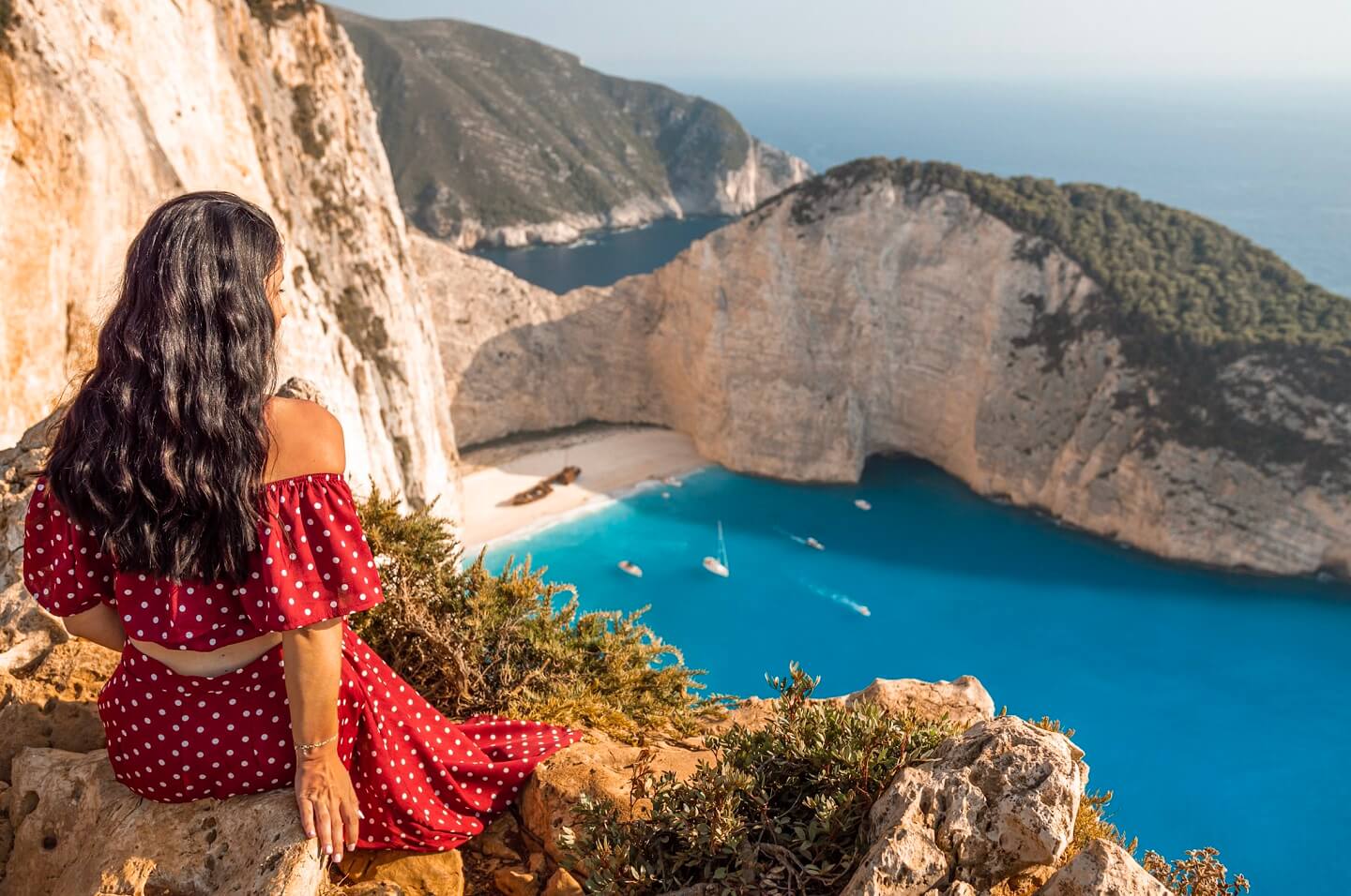 Girl in red dress on top cliff overlooking Zakynthos beach