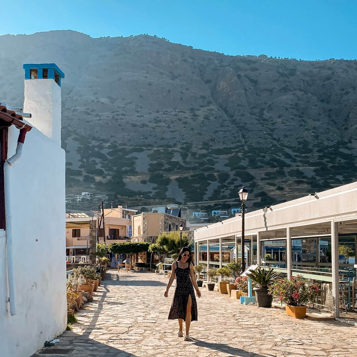 Stella walking in Plaka Crete streets with mountain behind her