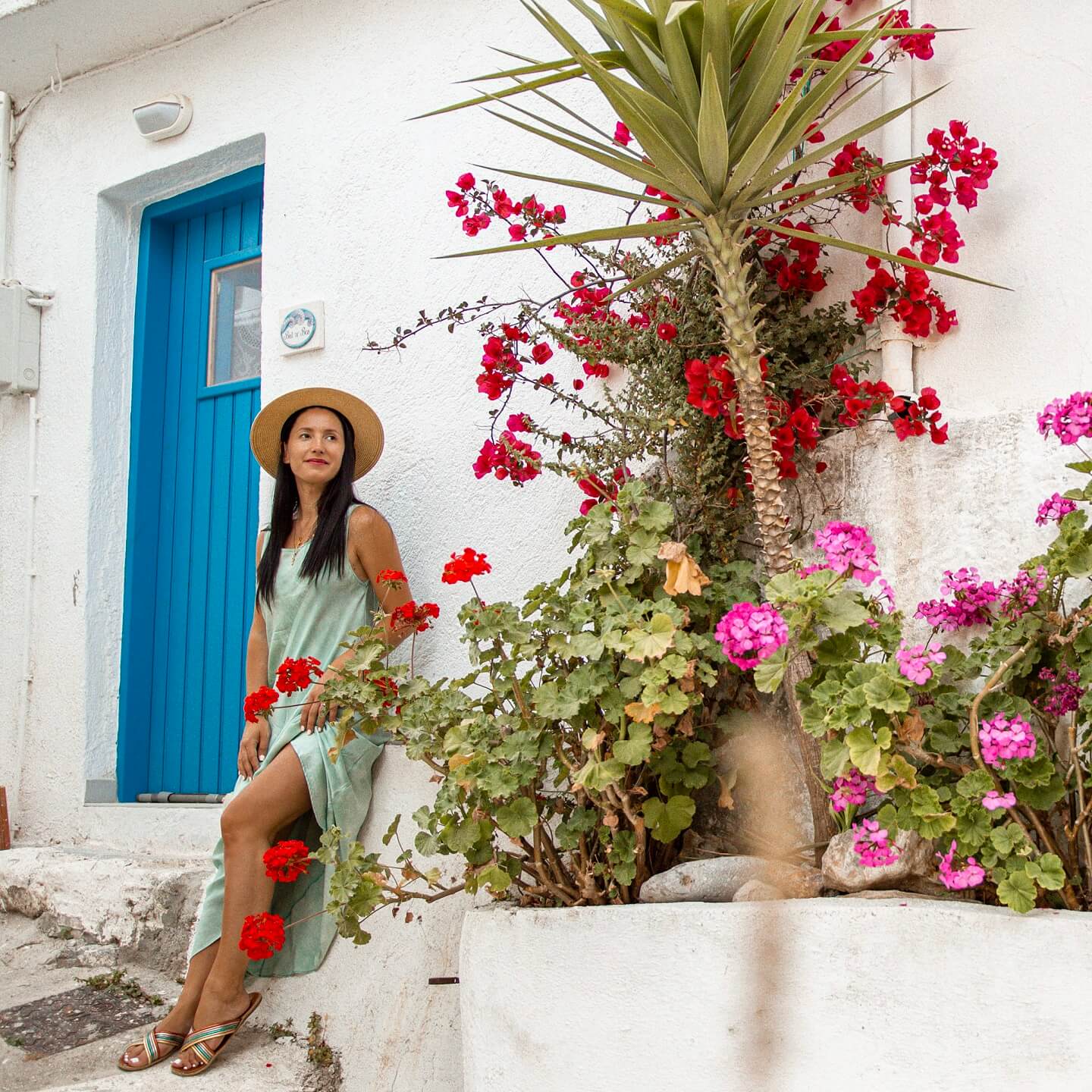Stella between red flowers and blue doors in Kritsa Crete