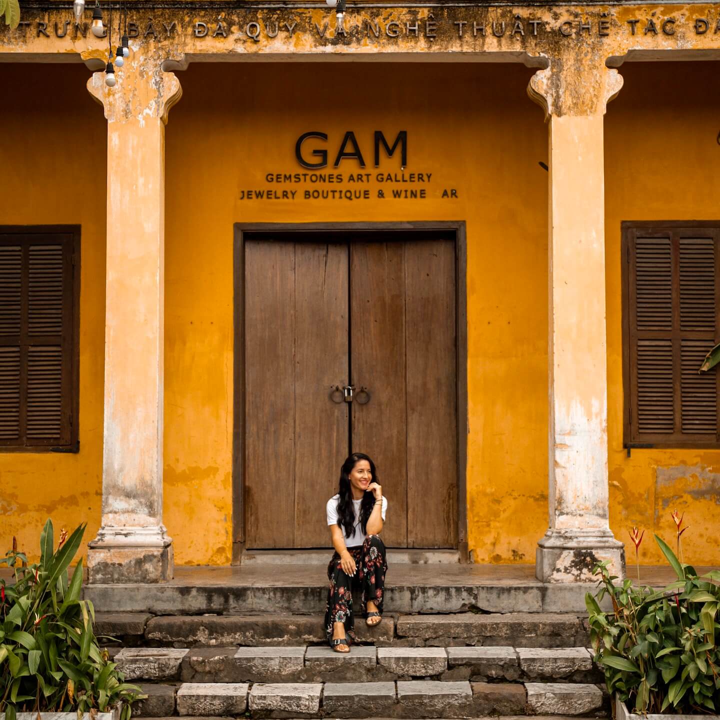 Stella sitting on the stairs of yellow building in Hoi An