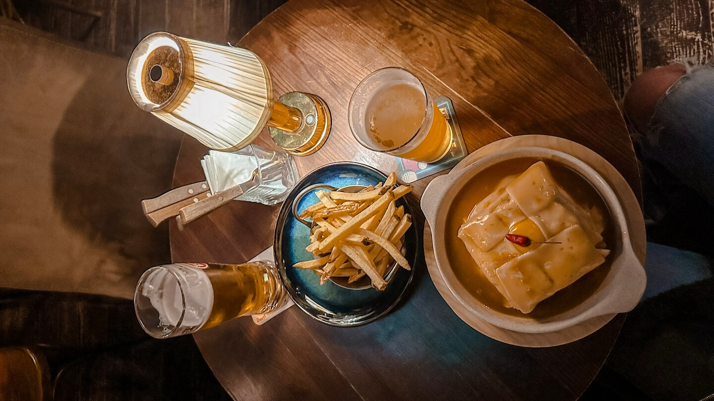 Traditional Francesinha sandwich with beers and fries in Porto